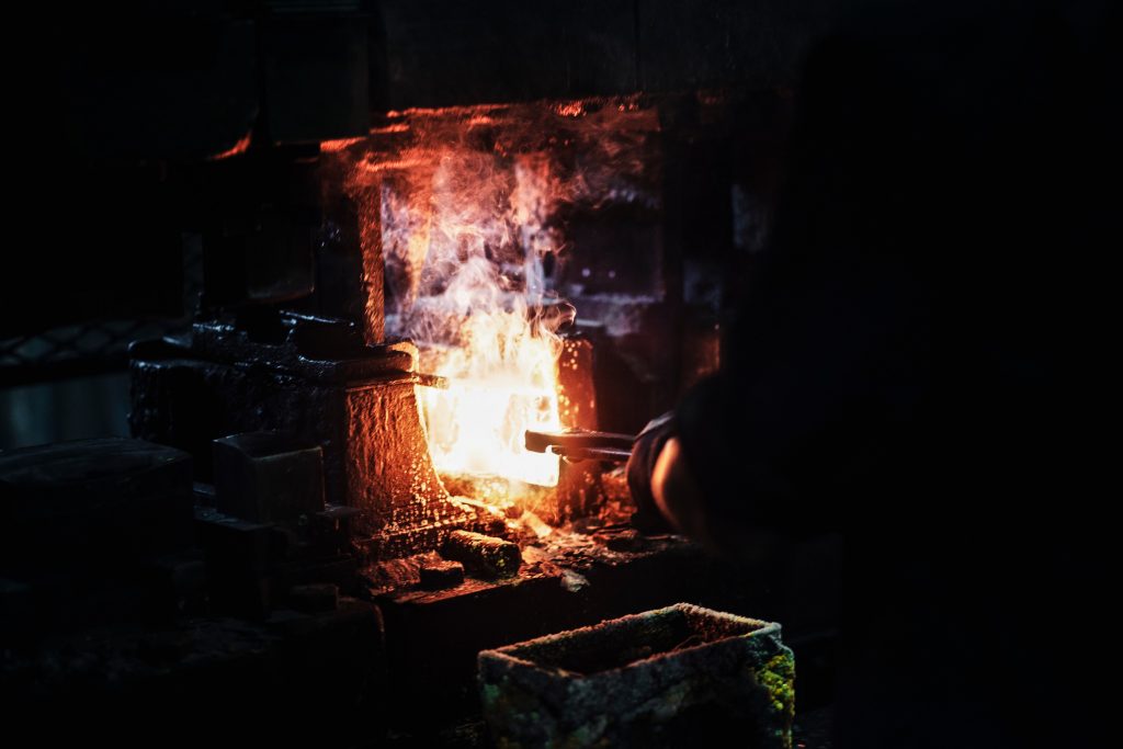 Blacksmith inserting axe head into forge fire