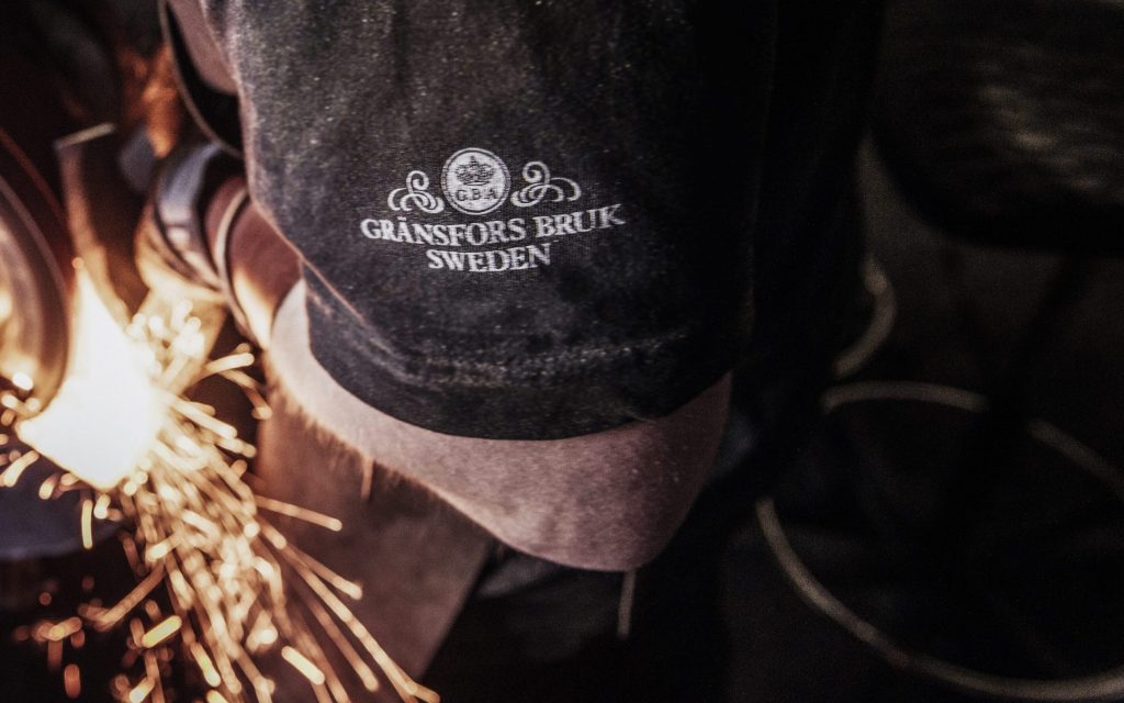 Blacksmith wearing Gransfors Bruk Sweden shirt with white logo on sleeve.